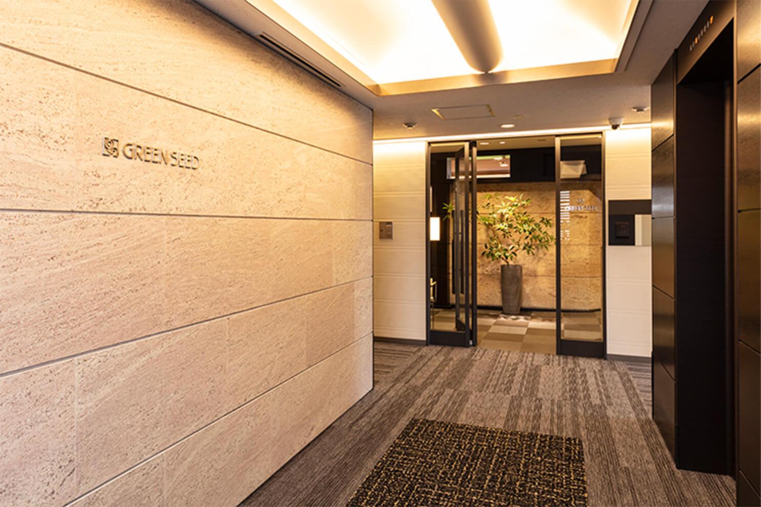 石材の壁とガラス扉が印象的な、洗練されたエントランス